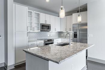 A modern kitchen with granite countertops and stainless steel appliances.